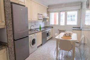 a kitchen with a table and a sink and a refrigerator at Apartamento Mayte in Siero