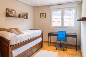 a bedroom with a desk and a bed with a blue chair at Apartamento Mayte in Siero