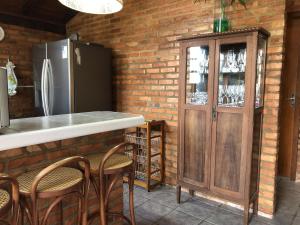 uma cozinha com um frigorífico e um balcão com cadeiras em Casa com Piscina e Acesso a Lagoa da Conceição NG0811 em Florianópolis