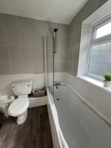 a bathroom with a toilet and a tub and a sink at Comfortable and spacious home. FREE Parking. in Gateshead