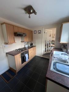a small kitchen with a stove and a sink at Comfortable and spacious home. FREE Parking. in Gateshead