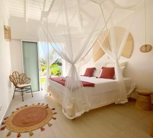 a bedroom with a bed with a mosquito net at Villa du Levant-6/8 pers-Piscine in Saint-François