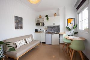 a living room with a couch and a table and a kitchen at Naim Guest House Nerja - Adults only in Nerja