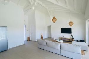 a living room with white furniture and a flat screen tv at Villa du Levant-6/8 pers-Piscine in Saint-François