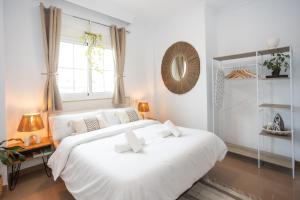 ein weißes Schlafzimmer mit einem großen weißen Bett und einem Fenster in der Unterkunft Naim Guest House Nerja in Nerja