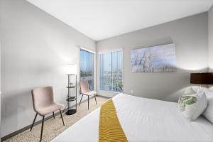 a bedroom with a bed and two chairs and two windows at Venice Beach Lux Retreat Coastal Apartment Haven in Los Angeles