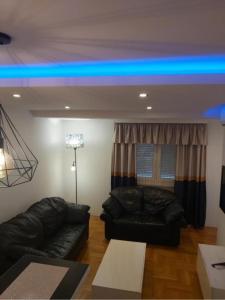 salon z 2 skórzanymi kanapami i niebieskim światłem w obiekcie Luks 2 apartment w mieście Banja Luka