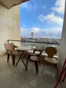 a balcony with a table and chairs and a window at Modern Apart in Heart of Amman in Rujm ash Sharāʼirah