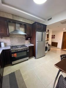 a kitchen with a stove and a refrigerator at Modern Apart in Heart of Amman in Rujm ash Sharāʼirah