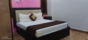 een slaapkamer met een bed met witte lakens en kussens bij CAUVERY PARADISE in Mayiladuthurai
