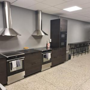 a kitchen with a stove and a counter with chairs at Rentalux Hostel in Timrå