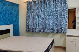 een slaapkamer met een bed en een blauw gordijn bij Luxurious 3BHK Flat in Magarpatta in Pune