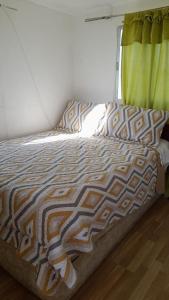 1 cama en un dormitorio con cortina verde en Hospedaje entre rokas, en Huasco
