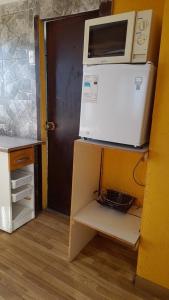 a microwave sitting on top of a refrigerator at Hospedaje entre rokas in Huasco