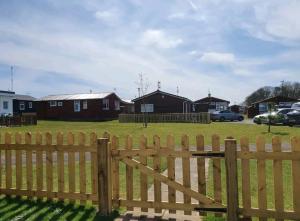 a wooden fence in front of a yard with houses at The Salty Sea Dog - Dog friendly and 2 minutes walk to the beautiful, golden beach in Bridlington