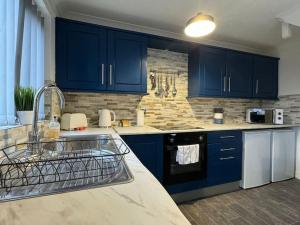 a kitchen with blue cabinets and white appliances at Hambleton Hideaway in Stokesley
