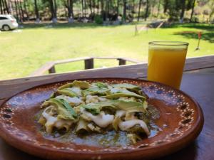 une assiette de nourriture sur une table avec un verre de jus d'orange dans l'établissement Rancho San Miguel, à Villa del Carbón