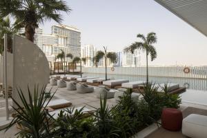 a rooftop patio with lounge chairs and palm trees at Business Travel Ready Studio at Upside Living in Dubai
