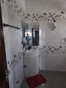 Baño blanco con lavabo y espejo en Spacieux havre de paix, en Ekpé