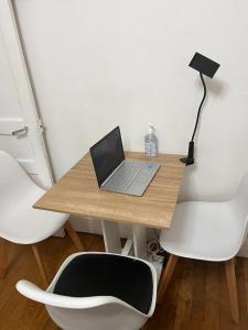 escritorio con ordenador portátil y 2 sillas blancas en chambre d'hote, en Issy-les-Moulineaux