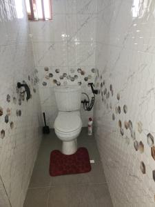 y baño con aseo en una pared de azulejos. en Spacieux havre de paix, en Ekpé