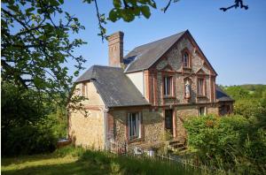 ein altes Backsteinhaus mit Kamin auf einem Hügel in der Unterkunft Charmant presbytère en Basse-Normandie in Crouttes