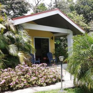 mały żółty dom z dwoma krzesłami i kwiatami w obiekcie Arenal Villas Tranquilas, free-standing equipped houses w mieście Nuevo Arenal