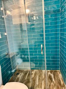 y baño con ducha de azulejos azules y aseo. en Apelles Butik Otel, en Seferihisar