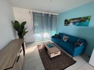 a living room with a blue couch and a table at Gwada FWI Coastal Residences in Le Gosier