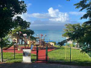 a park with a playground with the ocean in the background at Gwada FWI Coastal Residences in Le Gosier