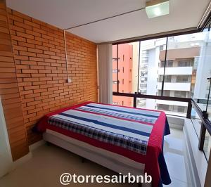 Cama en habitación con pared de ladrillo en Cobertura a poucos metros do mar, en Torres