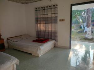 a bedroom with a bed and a large window at Surjasto Resort in Jaliapāra