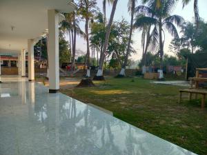 a courtyard with palm trees and water on the ground at Surjasto Resort in Jaliapāra