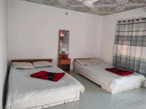 JaliapāraにあるSurjasto Resortのベッドルーム1室(赤い枕のベッド2台付)