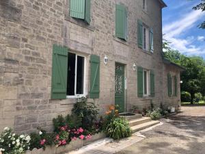 a stone building with green shutters and flowers on it at Le Moulin de Chamouilley in Chamouilley