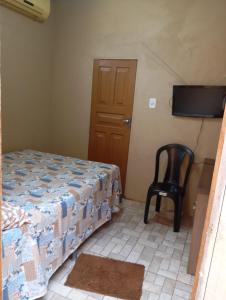 sypialnia z łóżkiem i krzesłem oraz telewizorem z płaskim ekranem w obiekcie HOSPEDARIA ITAPUÃ w mieście Santarém