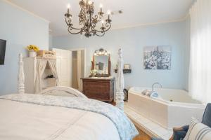Schlafzimmer mit einem Bett, einer Badewanne und einem Kronleuchter in der Unterkunft Grand Mansion-Blue Jay suite! in Fort Smith