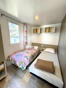 ein kleines Schlafzimmer mit zwei Betten und einem Fenster in der Unterkunft Mobil-home dans camping 4* in Saint-Laurent-du-Verdon