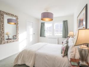 a white bedroom with a large bed and a mirror at Stalker's Cottage - Torridon in Achnasheen