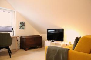 a living room with a yellow couch and a flat screen tv at strand Frische in Neustadt in Holstein