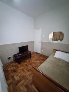 ein Schlafzimmer mit einem Bett und einem Tisch mit einem TV in der Unterkunft Comodidade e Segurança no Centro in Belo Horizonte