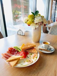 a table with a plate of breakfast food and a vase of flowers at MONARC Boutique ApartHotel - SELF CHECK-IN in Iaşi