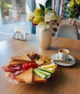 une assiette de nourriture sur une table avec un vase de fleurs dans l'établissement MONARC Boutique ApartHotel - SELF CHECK-IN, à Iaşi