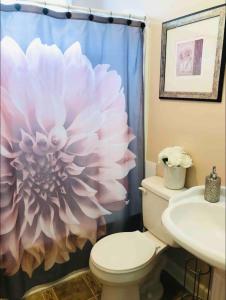 baño con aseo y cortina de ducha de flores en A Cozy Spot on Montague, en Charleston