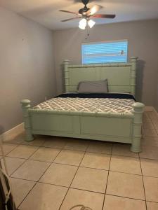 a bedroom with a green bed with a ceiling fan at 5 Mins from Clearwater Beach with Free Wi-Fi & TV in Clearwater