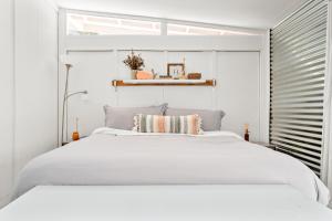 een witte slaapkamer met een wit bed en een raam bij Family Retreat Hot Tub & Private King Casita in Morongo Valley
