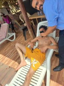 a man in yellow shorts sitting on a chair at Dreamers Lodge in Prampram