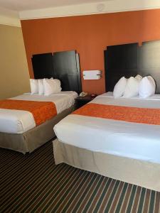Habitación de hotel con 2 camas y paredes de color naranja en Howard Johnson by Wyndham Historic Lake Charles, en Lake Charles