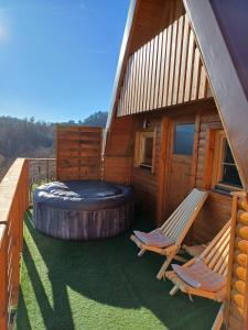 a cabin with two chairs and a large tire on the deck at Glamping Čelig 
