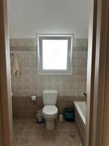ein Bad mit einem WC, einem Fenster und einer Badewanne in der Unterkunft ΔΩΜΑΤΙΟ ΜΕ ησυχία και θέα in Patras